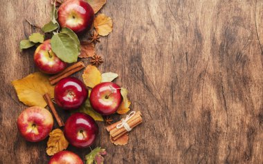 Sonbahar yemekleri geçmişi. Fındıklı olgun elmalar, dökülen yapraklar ve kırsal ahşap masa üzerinde tarçın. Üst Manzara. Boşluğu kopyala
