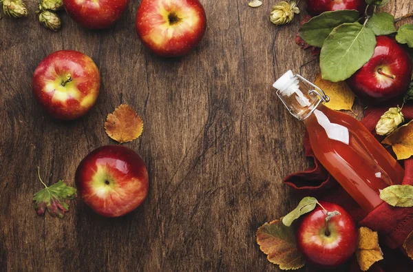 Apple cider vinegar. Bottle of fresh apple organic vinegar on wooden table background with cinnamon sticks, anise star, nuts and fallen leaves. Healthy organic food. Copy space