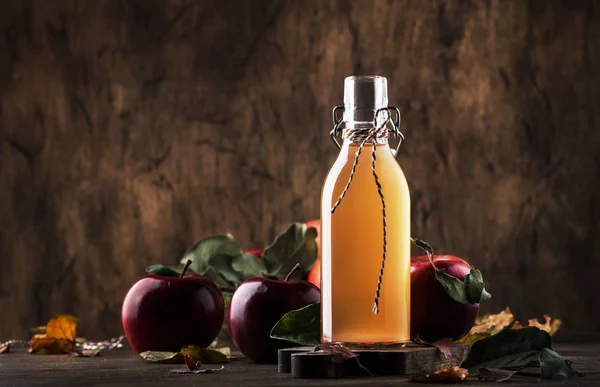 Apple vinegar. Bottle of apple organic vinegar made from fermented apples on wooden background. Healthy organic food.