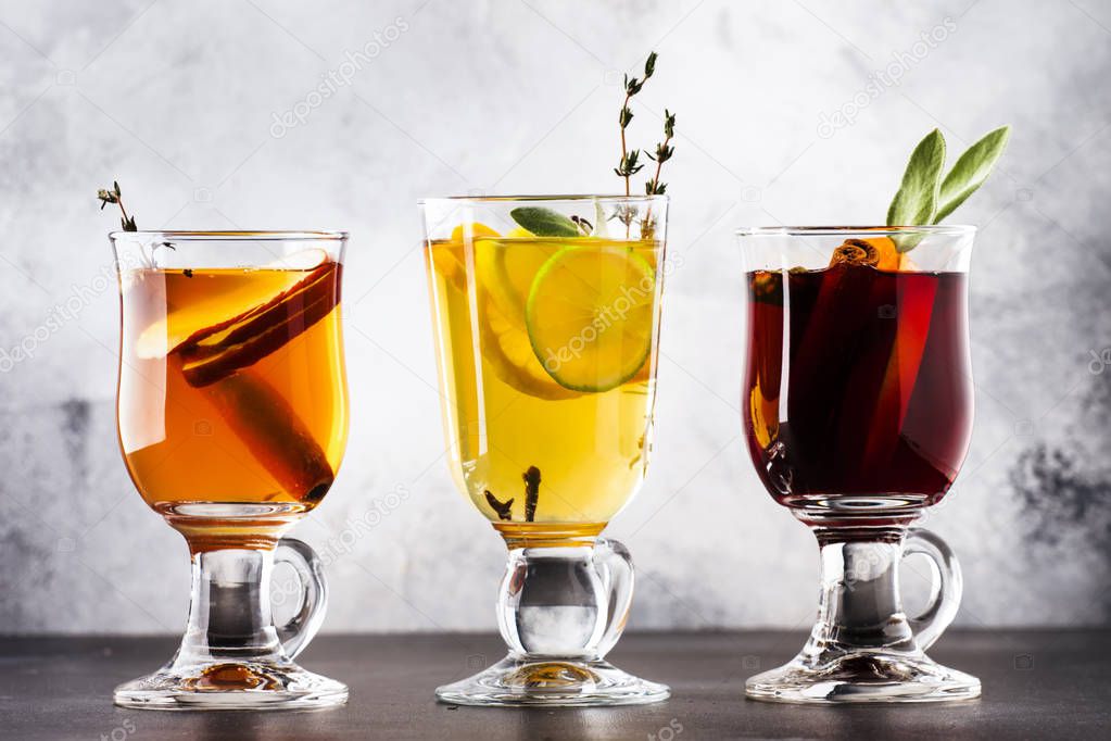 Mulled wine and mulled cider. Hot winter drinks and cocktails in glass mugs with spices and citrus fruit