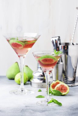 Pembe incirli alkollü martini bardakta gri masada bar aletleriyle, kopyalama alanı