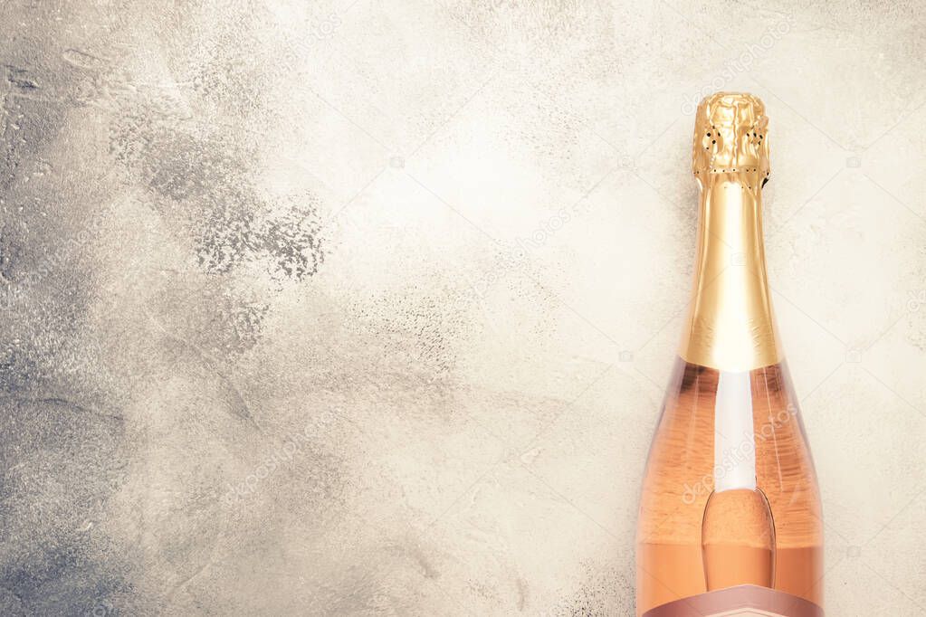 Bottle with pink sparkling wine or rose champagne and glasses, gray background with place for text, holiday or date concept, flat lay, top view