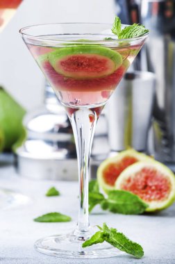 Pembe incirli alkollü martini bardakta gri masada bar aletleriyle, kopyalama alanı