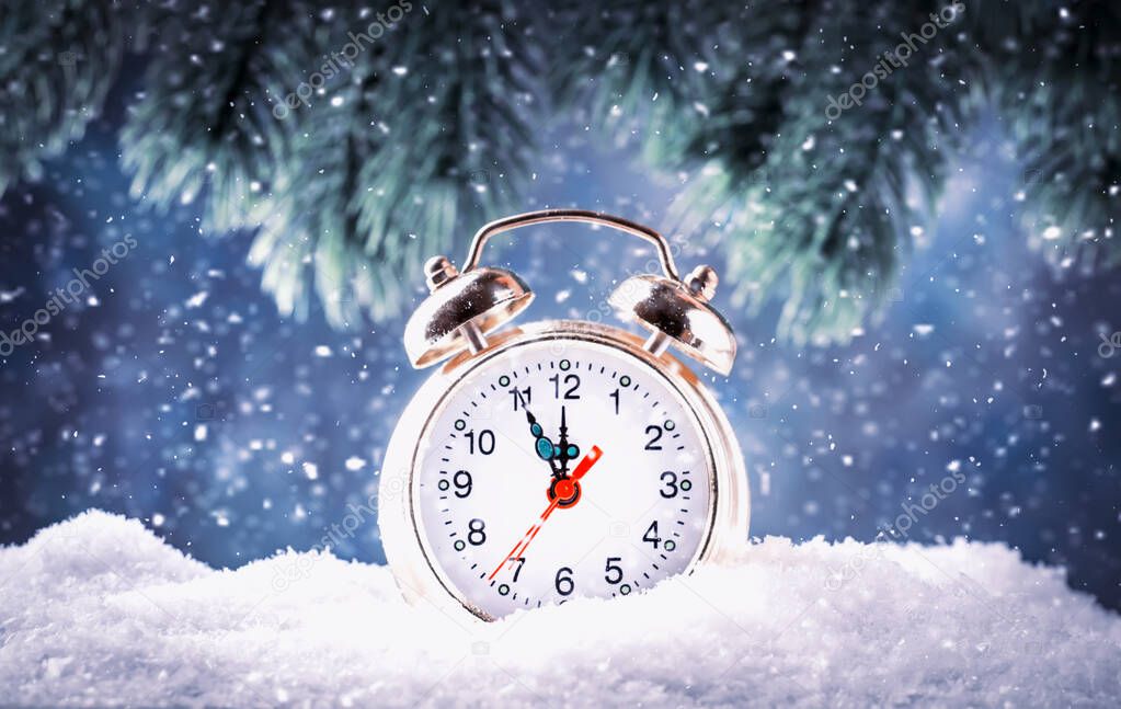 Christmas or New Year background with Golden alarm clock in snowdrifts on blue background with pine cones, fir tree, holiday lights counting last moments before Christmass Countdown to midnight