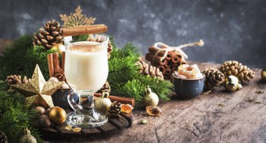 Noel ya da Yeni Yıl Alkollü Eggnog kokteyli - Süt, yumurta ve rom serpiştirilmiş sıcak kış içeceği, tarçın ve gri arka planda hindistan cevizi serpiştirilmiş, boşluğu kopyala