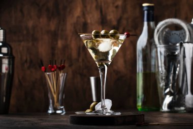 Martini kokteyli, kuru vermut, votka ve yeşil zeytin, bar aletleri ile klasik ahşap tezgah.