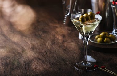 Martini kokteyli, kuru vermut, votka ve yeşil zeytin, bar aletleri ile klasik ahşap tezgah.