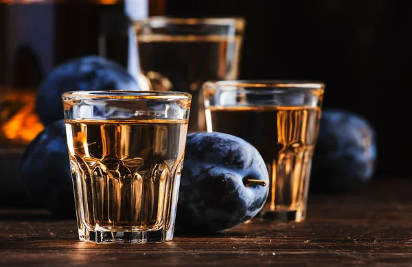 Slivovica - plum brandy or plum vodka, Balkan hard liquor, strong drink in shot glasses on old wooden table, copy space