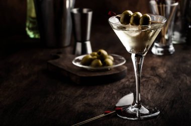Martini kokteyli, kuru vermut, votka ve yeşil zeytin, bar aletleri ile klasik ahşap tezgah.