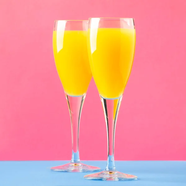 含橙汁 干香槟或玻璃杯中闪耀酒的含羞草酒鸡尾酒 蓝色粉红背景 复制空间 — 图库照片