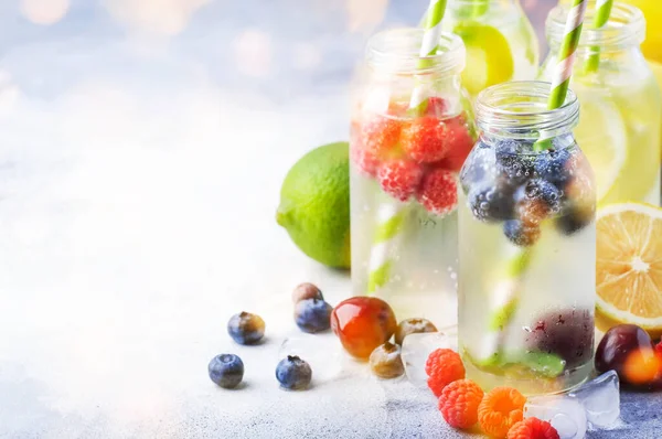 浆果和柑橘类水果在灰色石桌的玻璃瓶中注入夏季冷饮 复制空间 — 图库照片