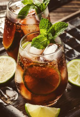 Güçlü alkol, limon suyu, kireç ve buz içeren Küba libre veya rom kola kokteyli, koyu arkaplan, çelik bar aletleri, kopyalama alanı