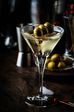Martini kokteyli, kuru vermut, votka ve yeşil zeytin, bar aletleri ile klasik ahşap tezgah.