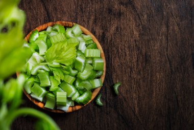 Taze yeşil kereviz parçalarını kaseye, eski ahşap arka plana, üst manzaraya, kopyalama alanına.