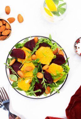 Portakallı pancar salatası, roka ve beyaz arka planda badem fıstığı. Vejetaryen sağlıklı yaz yemekleri. Üst Manzara. Boşluğu kopyala