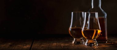 Buzsuz viski bardaklarda ve şişelerde, kırsal ahşap arka planda, uzay afişini kopyala 