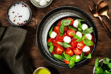 Olgun kırmızı domatesli Caprese salatası ve taze yeşil fesleğen yapraklı mozzarella peyniri. İtalyan yemeği. Üst manzara, ahşap arkaplan