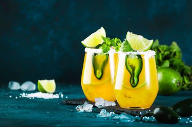 Baharatlı margarita kokteyli, tekila, mango suyu, jalapeno biberi, limon ve tuz, mavi arkaplan, kopyalama alanı.