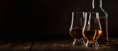 Buzsuz viski bardaklarda ve şişelerde, kırsal ahşap arka planda, uzay afişini kopyala 