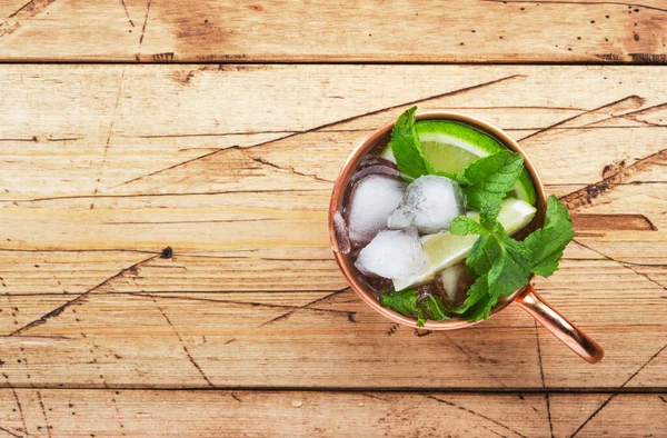 Limonlu, zencefilli, votkalı ve naneli bakır bardakta Moskova katırı kokteyli. Tahta masa, üst görünüm, kopyalama alanı