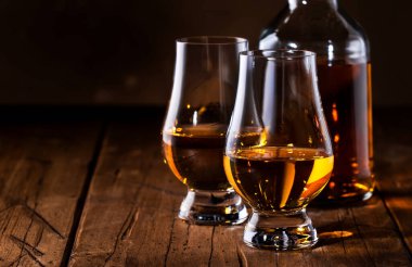 Buzsuz viski bardaklarda ve şişelerde, kırsal ahşap arka planda, kopyalama alanı