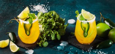 Baharatlı margarita kokteyli, tekila, mango suyu, jalapeno biberi, limon ve tuz, mavi arkaplan, kopyalama alanı.