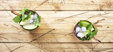 Limonlu, zencefilli, votkalı ve naneli bakır bardakta Moskova katırı kokteyli. Tahta masa, üst görünüm, kopyalama alanı