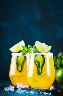 Baharatlı margarita kokteyli, tekila, mango suyu, jalapeno biberi, limon ve tuz, mavi arkaplan, kopyalama alanı.