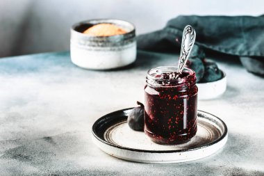 Cam kavanozda incir reçeli ve taze mavi incir. Ev yapımı hazırlıklar ve konserveler. Gri arkaplan, alanı kopyala
