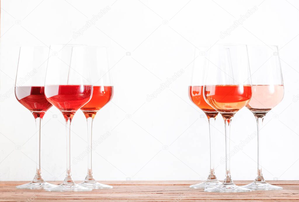 Rose wine glasses set on wine tasting. Tasting different varieties, colors and shades of pink wine concept. White background