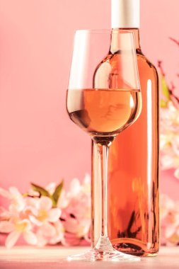 Şişe ve pembe çiçekli gül şarabı kadehi. Rosado, rosato ya da şarap tadımı, bar konsepti. Boşluğu Kopyala