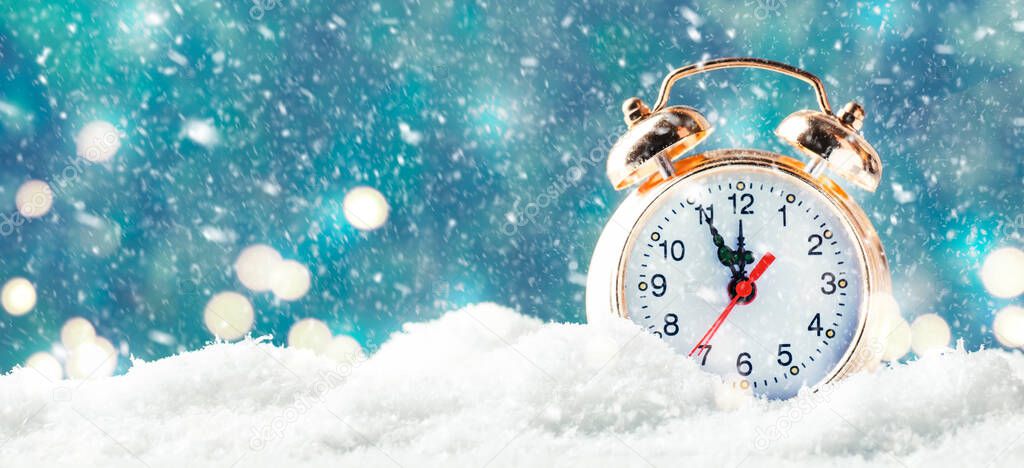 Christmas or New Year background with Golden alarm clock in snowdrifts on blue background with snow counting last moments before Christmas Countdown to midnight. 