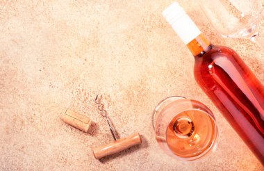 Bej masasının üzerinde şişe olan gül şarabı kadehi. Rosado, rosato ya da şarap tadımı, bar konsepti. Boşluğu kopyala, üst görünüm