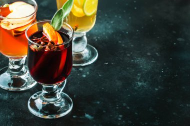 Kırmızı ve beyaz şaraptan sıcak şarap ve sıcak elma şarabı. Sonbahar veya kış içecekleri ve cam bardaklarda baharatlar ve narenciye meyveleriyle kokteyller.