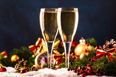 Mavi kar ve altın bokeh arka planda iki şampanya bardağı ve noel süslemesi. Mutlu yeni yıl kutlamaları. Seçici odak ve küçük alan derinliği