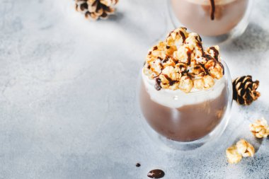 Krem şantili, patlamış mısırlı ve bej arka planda gözlüklü karamel kaplı soğuk kış çikolatalı tatlılar.