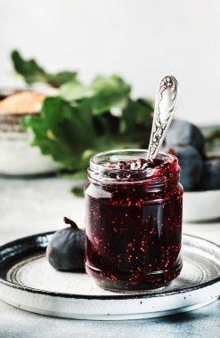 Cam kavanozda incir reçeli ve taze mavi incir. Ev yapımı hazırlıklar ve konserveler. Gri arkaplan, alanı kopyala