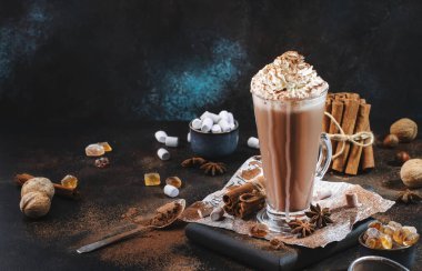 Uzun bardakta sıcak çikolata ve siyah masada krem şanti. Koyu mavi arka plan. Boşluğu kopyala 