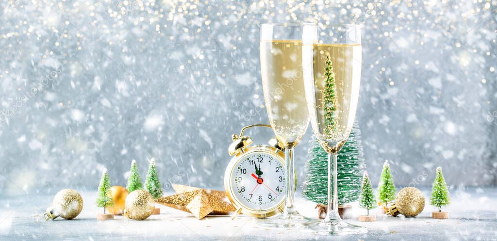 Two champagne glasses and christmas decoration over gray golden bokeh under the snow background. Happy New Year Celebration. Selective focus and small depth of field