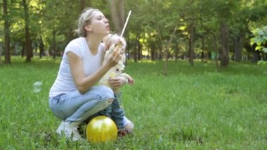 Bir kadın ve bir çocuk parkta sabun köpüğü ile oynamak.