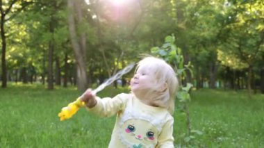 Sabun köpüğü parkta üfleyen bir çocuk.