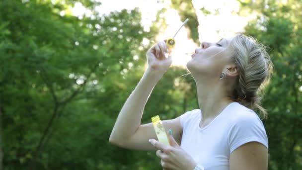 Giovane donna che soffia bolle di sapone nel parco. — Video Stock