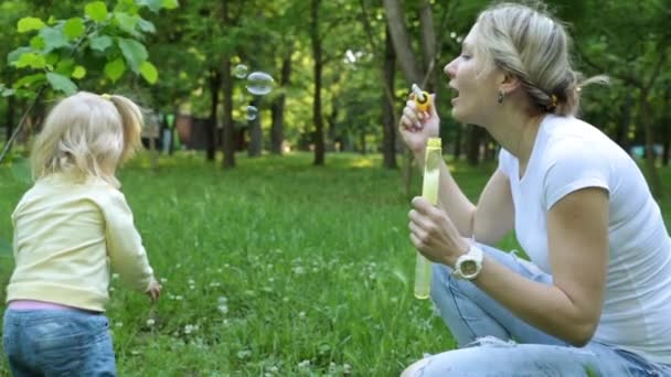 Uma jovem está brincando com uma criança no parque . — Vídeo de Stock