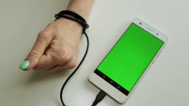 The hand is tied to the phone with a green screen. Dependence on the smartphone. — Stock Video