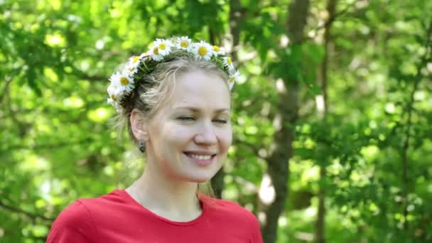 Belle femme avec une couronne de marguerites sur un fond d'arbres . — Video