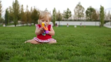 Bir çocuk parkta yeşil çim üzerinde oynuyor.