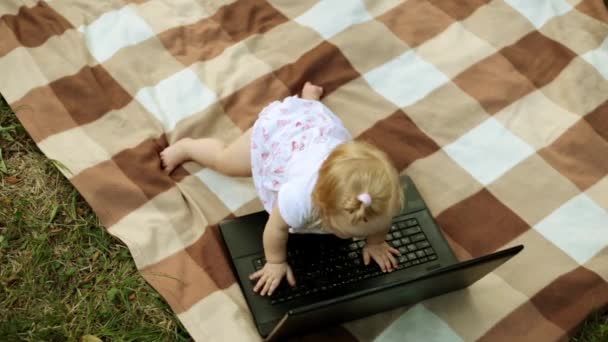 Klein kind rommelt met een laptop in de natuur. — Stockvideo