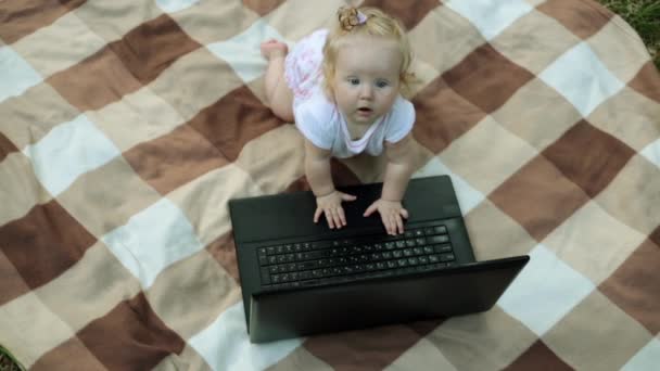 Klein kind rommelt met een laptop in het park — Stockvideo