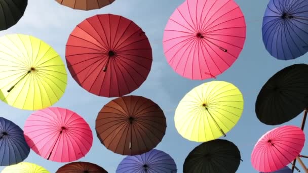 Много цветных зонтиков против неба . — стоковое видео