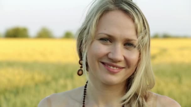 Portrait of a young beautiful woman against a wheat field background. — Stock Video